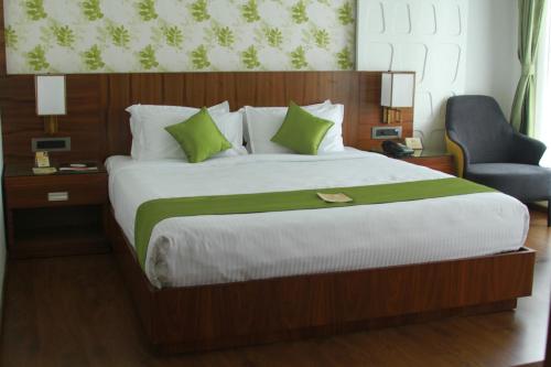 a bedroom with a large bed and a chair at Hotel Ceasar Palace Kottayam in Kottayam