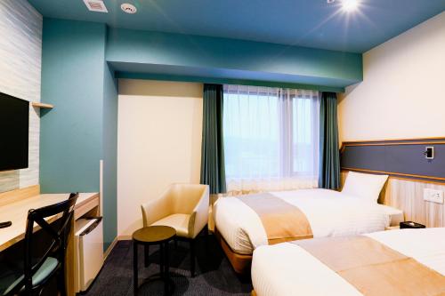 una camera d'albergo con 2 letti e una scrivania di Hotel Wing International Select Kumamoto a Kumamoto