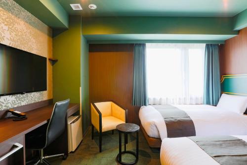 a hotel room with two beds and a flat screen tv at Hotel Wing International Select Kumamoto in Kumamoto