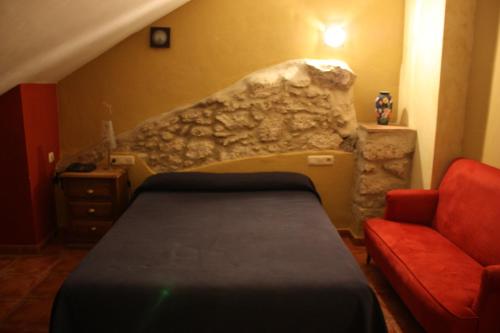 a bedroom with a bed and a stone wall at Hotel Don Pero in Alora