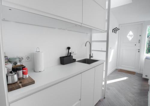 a white kitchen with a sink and a counter at Waterland Hoge Huis in Monnickendam