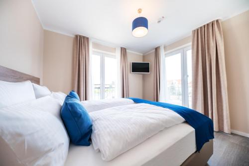 a bedroom with a bed with white and blue pillows at AKZENT Apartmenthotel Binz in Binz