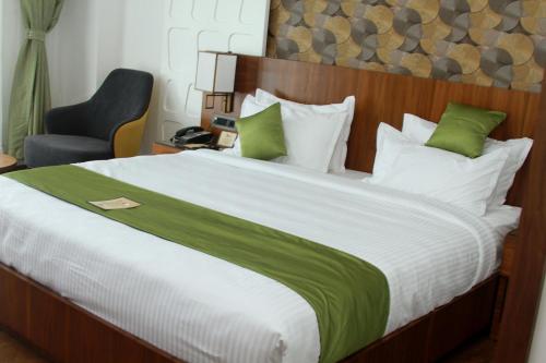 a bedroom with a large bed and a blue chair at Hotel Ceasar Palace Kottayam in Kottayam