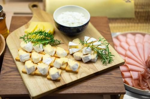 a wooden cutting board with cheese and a bowl of rice at Vessel Hotel Campana Susukino in Sapporo