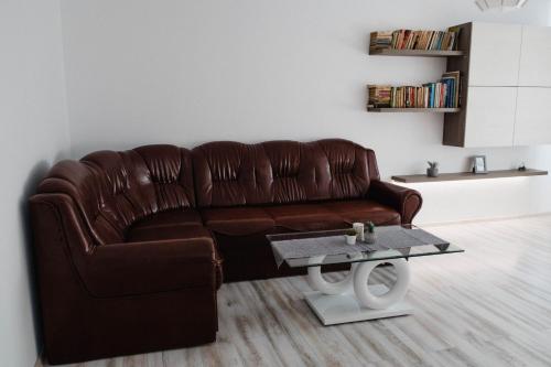 ein braunes Ledersofa im Wohnzimmer mit einem Tisch in der Unterkunft Good Vibes Apartment in Câmpulung Moldovenesc