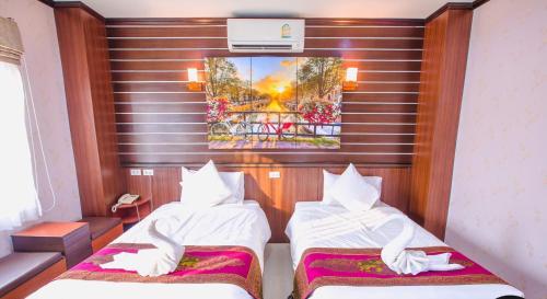 a hotel room with two beds and a painting on the wall at BANDER HOTEL in Phu Khieo