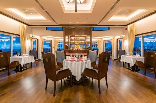 a dining room with tables and chairs and windows at Heritage Line Ginger Cruise - Halong Bay & Lan Ha Bay in Ha Long