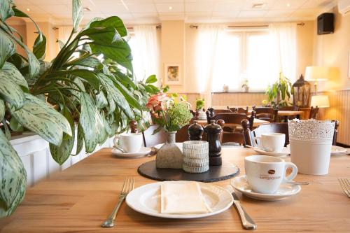 a wooden table with plates and cups and plants at Brauers Landarthotel GmbH in Daun