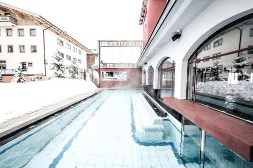 a swimming pool in a building with a wooden bench at Hotel Rigele Royal Superior in Obertauern