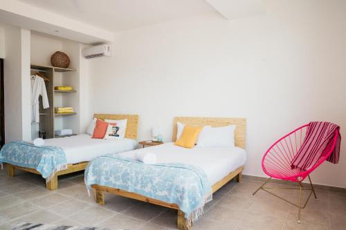 a bedroom with two beds and a pink chair at dewl estudios & residences : THE KAHLO in Playa del Carmen
