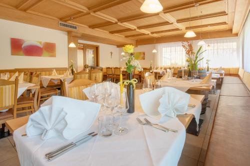a restaurant with tables and chairs with white tablecloths at Gasthof Hotel Terzer in Cortaccia