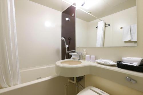 W łazience znajduje się umywalka, toaleta i lustro. w obiekcie Almont Inn Tokyo Nihonbashi w Tokio