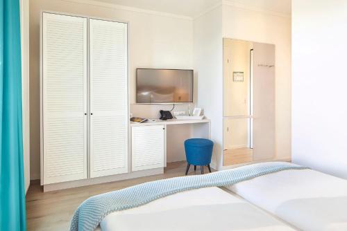 a bedroom with a bed and a desk with a tv at Familotel Strandkind in Pelzerhaken
