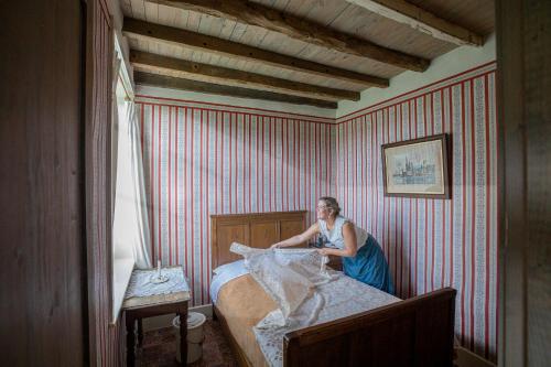 a woman sitting on top of a bed in a room at Barak de Vinck in Ypres