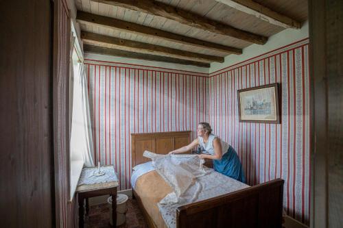uma mulher sentada em cima de uma cama num quarto em Barak de Vinck em Ypres
