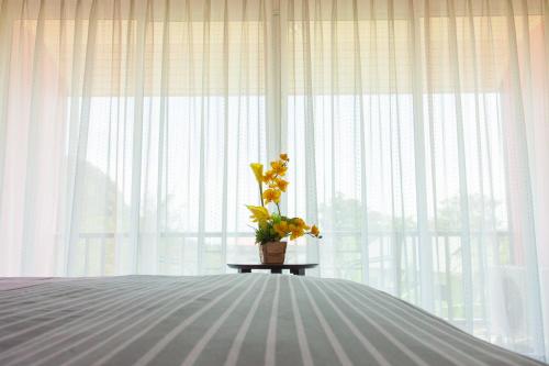 a vase of flowers on a table in front of a window at Nam Talay Resort in Pran Buri