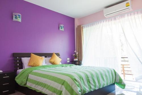 a purple bedroom with a bed and a window at Nam Talay Resort in Pran Buri