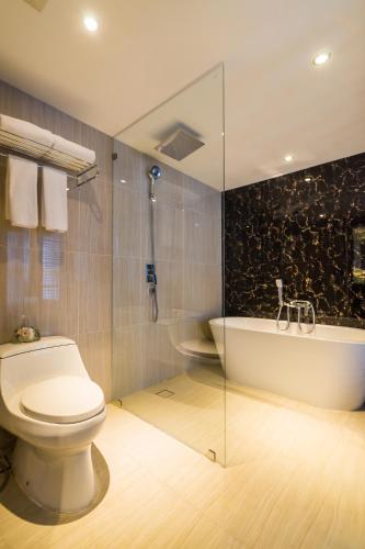 a bathroom with a toilet and a bath tub at Citrus Grande Hotel Pattaya by Compass Hospitality in Pattaya South