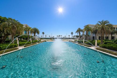 a swimming pool with palm trees in a resort at Las Arenas Balneario Resort in Valencia