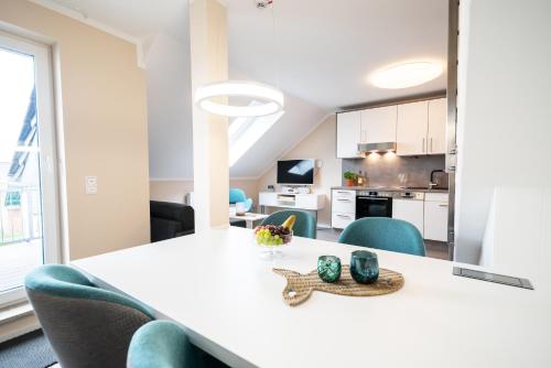 a dining room with a white table and blue chairs at AKZENT Apartmenthotel Binz in Binz