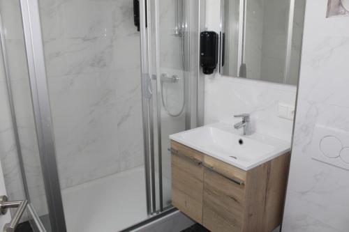 La salle de bains blanche est pourvue d'une douche et d'un lavabo. dans l'établissement Hideaway Obertraun, à Obertraun