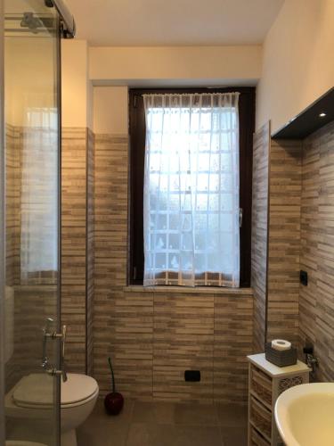 a bathroom with a toilet and a sink and a window at Maison Jean-Luc - app Vittorio in Bra
