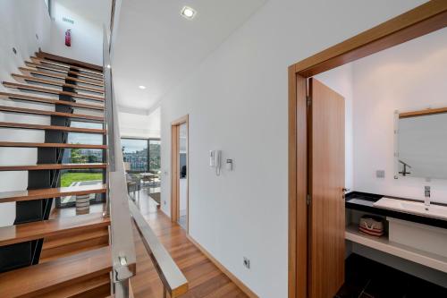 - un escalier dans une maison dotée de murs blancs et de parquet dans l'établissement Vila Papagaio Verde by An Island Apart, à Funchal