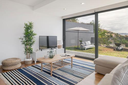 a living room with a couch and a table at Vila Papagaio Verde by An Island Apart in Funchal