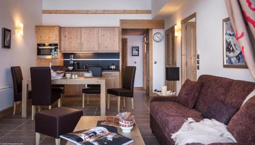 sala de estar y cocina con sofá y mesa en CGH Résidence Boutique Le Lodge des Neiges, en Tignes