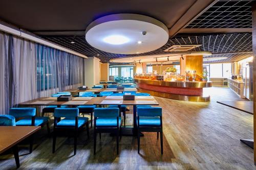 a dining room with tables and blue chairs at Insail Hotels (Pazhou Exhibition Center KeCun Metro Station Dunhe Road Branch Guangzhou) in Guangzhou