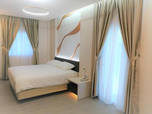 1 dormitorio con 1 cama y 2 ventanas grandes en Legacy Hotel Ipoh en Ipoh