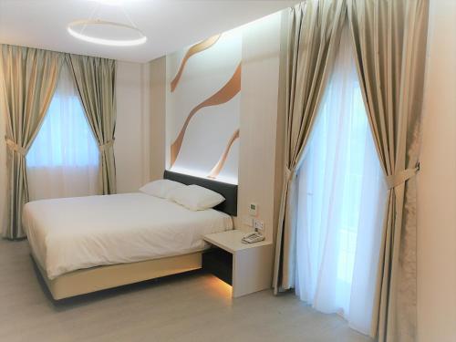 a bedroom with a bed and two large windows at Legacy Hotel Ipoh in Ipoh
