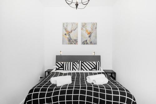 a bedroom with a black and white bed with two pillows at First Central Apartments by Renters in Warsaw