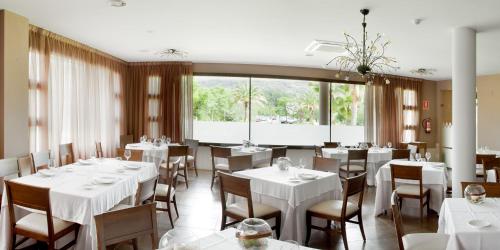 a restaurant with white tables and chairs and a large window at Hotel Balneario Valle del Jerte in Valdastillas