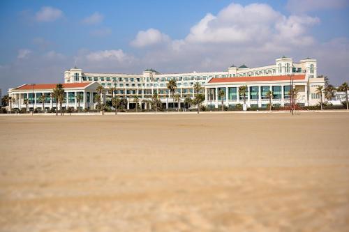 a large white building with palm trees in front of it at Las Arenas Balneario Resort in Valencia