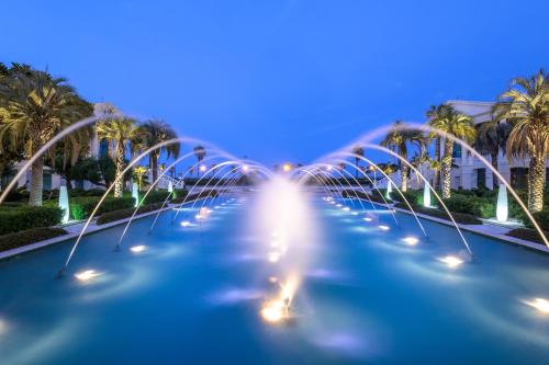 a row of water fountains at night with palm trees at Las Arenas Balneario Resort in Valencia