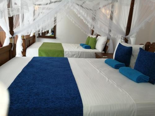 2 letti in una camera con blu e bianco di Suriya Homestay Mirissa a Mirissa