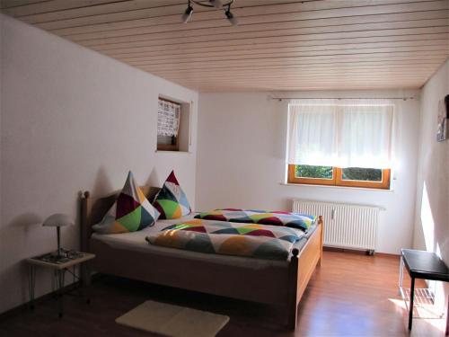a bedroom with a bed with colorful pillows and a window at Ferienwohnung Maria in Todtmoos