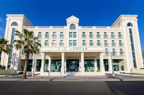 a large white building with palm trees in front of it at Las Arenas Balneario Resort in Valencia