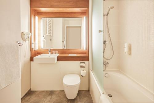 a bathroom with a toilet and a sink and a mirror at Campanile Bydgoszcz in Bydgoszcz