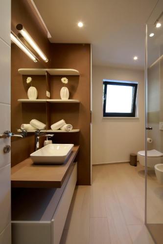 a bathroom with a sink and a toilet and a window at MODENA MARIS-heated pool-grill-relax-jacuzzi apartments in Ičići