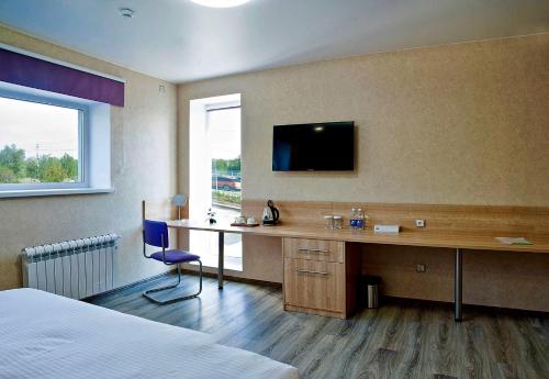 ein Hotelzimmer mit einem Schreibtisch und einem TV an der Wand in der Unterkunft Hotel Vzlet in Orenburg