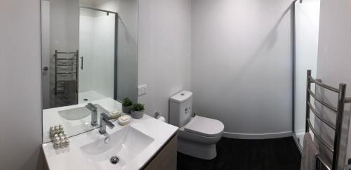 a white bathroom with a sink and a toilet at Central Park Gemini Apartments in Hamilton