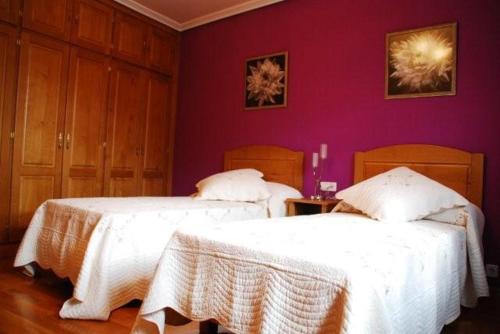 two beds in a room with purple walls at El Encinedo in Genevilla