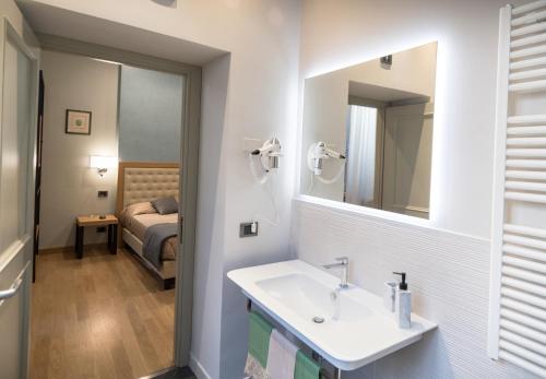 uma casa de banho com um lavatório, um espelho e uma cama em Brunelli B&B em Assis