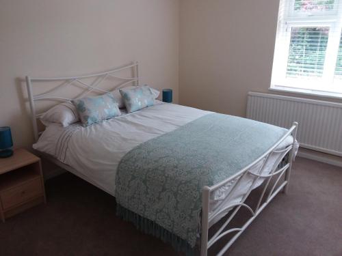 1 dormitorio con cama blanca y almohadas azules en Alderman Peel High School Bungalow, en Wells-next-the-Sea