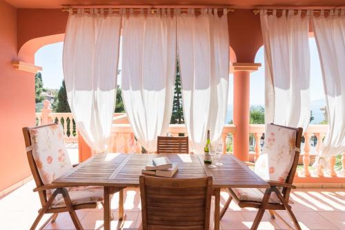una mesa de madera y sillas en un balcón con cortinas blancas en LU&CIA VILLA CANDADO, en Málaga