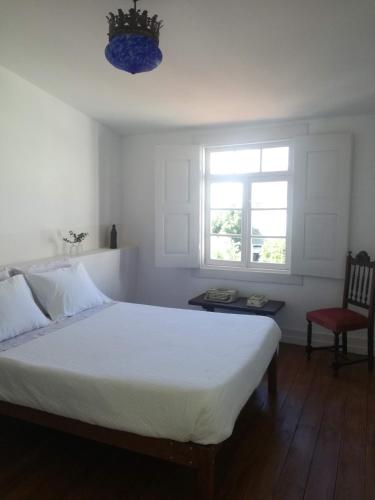 sypialnia z białym łóżkiem i czerwonym krzesłem w obiekcie Casa de Guadalupe w mieście Braga
