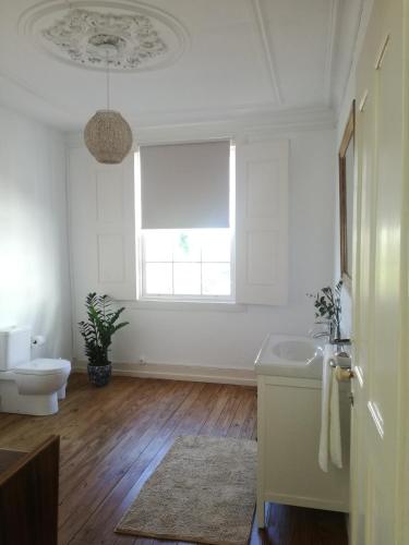 a white bathroom with a toilet and a window at Casa de Guadalupe in Braga