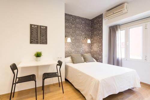1 dormitorio con 1 cama, mesa y sillas en LU&CIA City Beach Malagueta 2, en Málaga